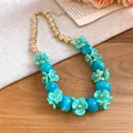 Close-up of acrylic flower beaded necklace with turquoise petals and blue beads. - Light Green