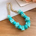 Detailed close-up of a light blue acrylic flower beaded necklace in resort style. - Cyan