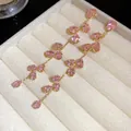 Primo piano di eleganti orecchini pendenti con nappe in zircone rosa in un portagioie - Rosa