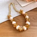 Close-up of acrylic oval beaded necklace with amber flower charms in resort style - Brown