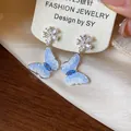 Dettaglio macro di orecchini a farfalla in argento S925 con zirconi blu brillanti. - Blu