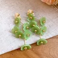 Detailed macro view of elegant green acrylic floral dangle earrings with gold-toned metal - Gold with Green