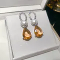Nahaufnahme von vergoldeten Zirkonia-Perlenohrringen mit funkelnden orangefarbenen Tropfen. - 925 Silberstift Stil (HE34277) / Silber-Kaffee