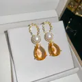 Nahaufnahme von 18 Karat vergoldeten Ohrringen mit Perlen und orangefarbenen Steinen - 925 Silberstift Stil (HE34277) / Goldbraun