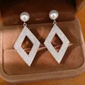 Gros plan de boucles d'oreilles losanges élégantes avec zircons brillants et perles - Style Perle Losange Creux / Argent