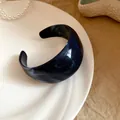 Makroaufnahme eines dunkelblauen marmorierten Harz-Armreifs auf einem weißen Teller. - Unregelmäßiger Wisch-Stil / Dunkelblau