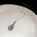 Exquisite macro shot of a pear-shaped zircon pendant necklace on a white ceramic plate - Necklace - Silver / White
