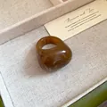 Detailed view of an amber resin ring with a marbled pattern on a linen background - Brown