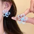 Elegant light blue hollow-out flower ear studs for women, delicate spring floral jewelry. - Blue