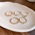 Detailansicht von fünf goldenen offenen Ringen mit Perlen und Kristallen auf einer Schale. - offener Ring / 5-teiliges Set / Gold