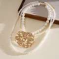 Close-up of multi-layer pearl necklace with statement hammered gold metal pendant - Necklace - Gold - White / 135cm
