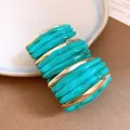 Close-up view of a marbled turquoise acrylic and gold-tone metal segmented bracelet. - Green