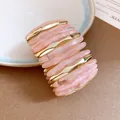 Detailed close-up showing the marbled pink acrylic and gold-toned segmented bracelet - Pink