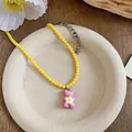 Close-up detail of yellow beaded necklace featuring a cute pink resin bear pendant - Yellow/Pink