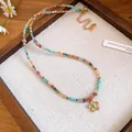 Detailed view of bohemian colorful beaded necklace with gold flower pendant - Colorful