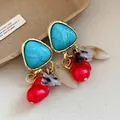 Primer plano de pendientes vintage dorados con piedras azules y borlas de perlas - Pin de Plata-Azul-Rojo