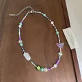 Colorful handmade beaded necklace featuring butterfly and flower charms on a wooden surface. - Silver/Multicolor