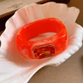 Close-up of a vibrant orange resin square bangle with a large central orange gemstone - Orange