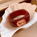 Close-up detail of luxury wine red resin square bracelet with faceted champagne crystal - Brown