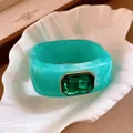 Close-up of a turquoise resin square bracelet featuring a faceted emerald green gemstone - Green