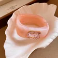 Close-up of elegant pink marbled resin square bangle with a large pink crystal detail. - Pink