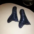 Primo piano di orecchini con pavé di strass neri in un'unica forma di coda di sirena vintage - Canna di fucile