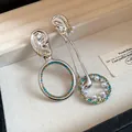 Dettaglio macro di orecchini asimmetrici con perle bianche e pietre di zircone blu - Argento