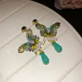 Close-up view of elegant butterfly earrings featuring zircon crystals and pearl accents. - Green