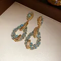 Detailed view of elegant gold feather water drop earrings with blue gemstones and stones. - Gold-Blue