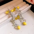 Macro view of handmade long drop earrings featuring resin lemons and white pearls - Earrings / Silver Needle / Silver/Yellow