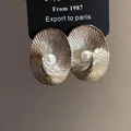 Detail of oval textured 18k gold plated stud earrings with a central pearl on display card - Alloy Oval Textured Silver Style / Silver