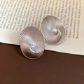 Macro detail showing the radial texture and pearl of these oval silver needle stud earrings - Oval Textured Style / Silver