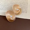 Elegant 18k gold plated oval textured stud earrings featuring a central pearl detail - Oval Textured Style / Gold