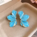 Macro view of stylish blue flower stud earrings with golden alloy wavy metal edges - Blue