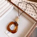 Detail of amber resin oval pendant necklace with woven bead on brown leather cord - Smooth Oval Pendant (HN12379) / Coffee