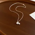 Detailed macro view of silver peanut and heart charms on a delicate silver chain necklace - Peanut Pearl Style / Silver