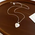 Detailed shot of a silver heart-shaped pendant with a center pearl on a box chain - Heart Pearl Style / Silver