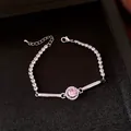 Dettaglio di un bracciale argentato con zircone rosa centrale in scatola nera. - Argento-Rosa