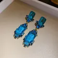 Elegant vintage style geometric drop earrings featuring large faceted blue crystals. - Earrings (Silver Pin - Gold) / Blue