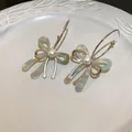 Detailed macro view of silver bow earrings with colorful resin and a pearl center - Silver and Green