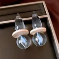 Macro view of transparent teardrop earrings with blue swirl and wood detail. - Silver Post Transparent Coffee Style