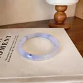 Gros plan détaillé du bracelet en calcédoine translucide violet clair sur un livre - Style 8