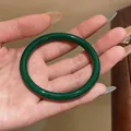 Gros plan détaillé montrant la texture translucide d'un bracelet jonc en calcédoine vert foncé - Style 1