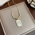 Detailed macro view of elegant gold necklace featuring rhinestone letter H pearl pendant - Gold