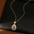 Dettaglio ravvicinato di una collana con ciondolo a goccia dorata con pietre CZ brillanti. - Oro