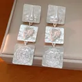 Detail view of silver geometric square earrings with surreal anatomical relief - Silver