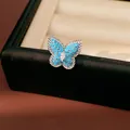 Macro detail of a butterfly ear clip with blue stones and a central marquise zircon - Butterfly Ear Cuff / Blue