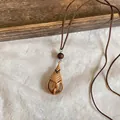Detailed view of a hand-woven rattan waterdrop pendant on a brown leather cord necklace. - Water Drop Style