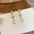 Detail view of elegant starburst zircon earrings with white pearls in 18K gold plating. - Gold