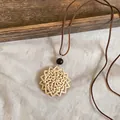 Close-up detail of retro woven rattan pendant necklace with dark brown leather cord - Radiating Sun Flower Style